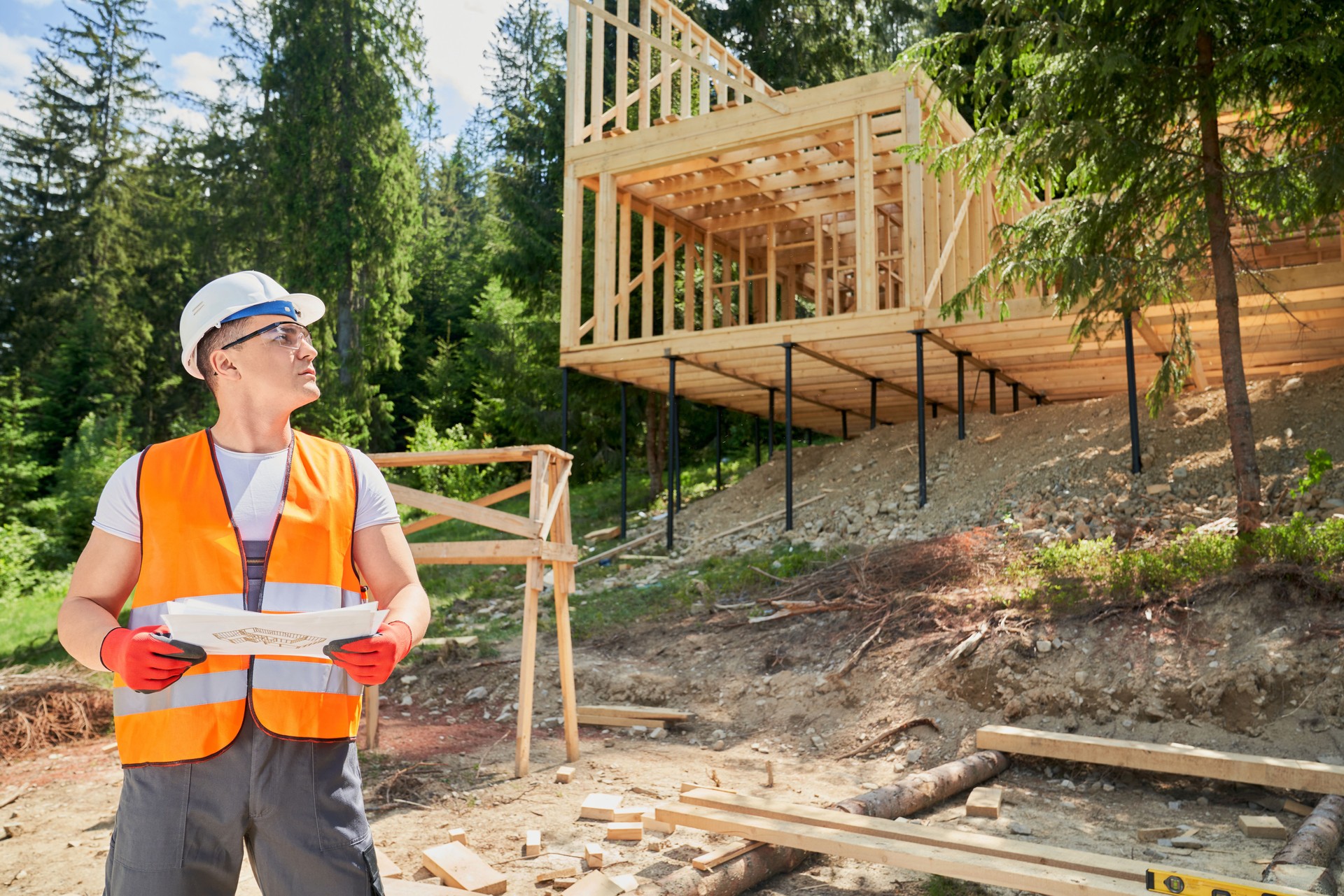 Man wearing vest and helmet, holding paper, project, looking up, thinking, constructing.